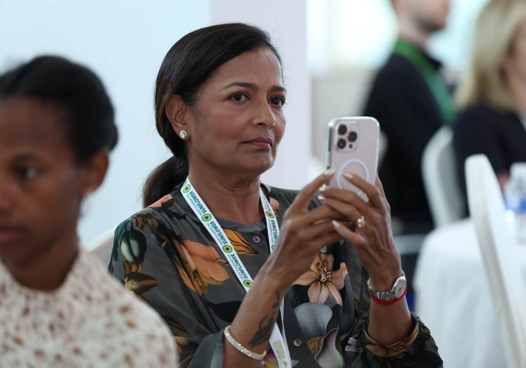 Aarti Shah's mother taking photos on her phone at Aurora50's Inclusive Workplaces Summit. Aarti, a Bollywood actress and power lifter, is a person of determination who spoke at the summit.