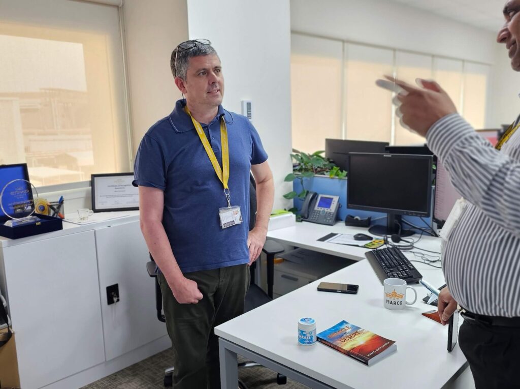 Marco Giovannoli, Etihad engineer and author of Miracle in the Desert, at work (with his book) in a supplied image. Mr Giovannoli was a speaker at Aurora50's Inclusive Workplaces Summit 2024.