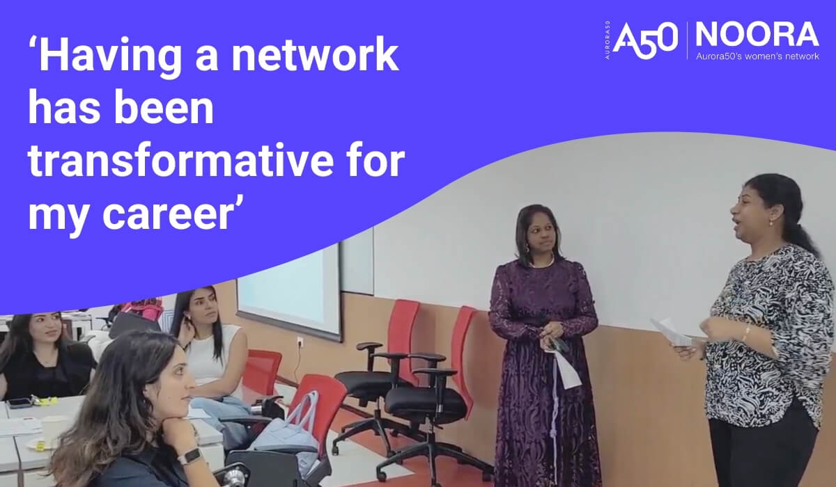 Blog post graphic shows Aurora50 and NOORA logos with strapline Aurora50's women's network and the text 'Having a network has been transformative for my career'. Photo shows Mamatha Shyamala speaking at a NOORA workshop in May 2025 about her career journey as NOORA members listen.